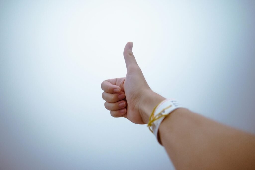 A hand giving a thumbs up gesture symbolizes approval and positivity.